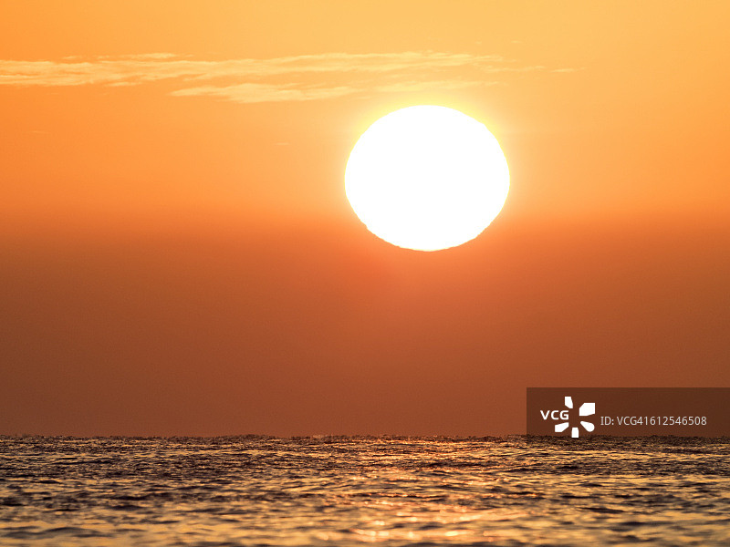一幅日出的画面，太阳从海上升起，橘黄色的云。西班牙图片素材