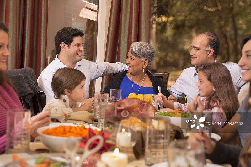 多民族家庭在祖母家享受圣诞晚餐。图片素材