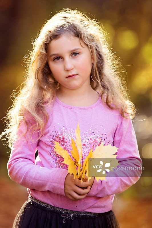 一个女孩抱着秋叶的肖像图片素材