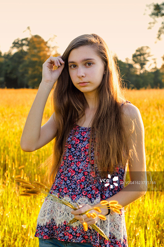 一个十几岁的女孩在阳光明媚的夏日田野里的肖像图片素材
