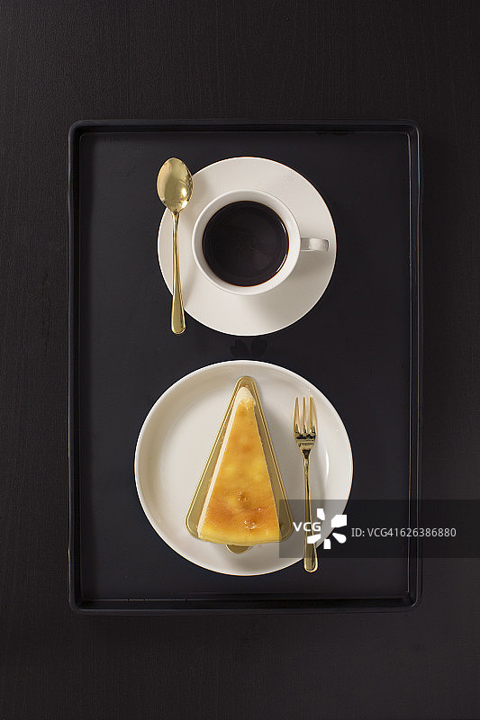 平躺俯视视图黑咖啡和奶酪蛋糕在黑色的背景。图片素材