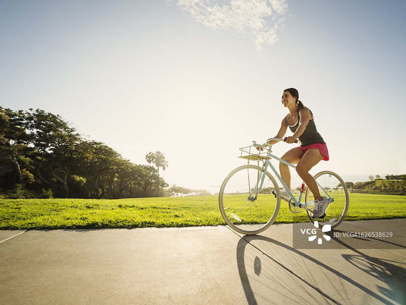 美国，加州，拉古纳海滩，年轻女子在公园骑自行车图片素材