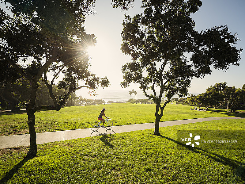 美国，加州，拉古纳海滩，年轻女子在公园骑自行车图片素材