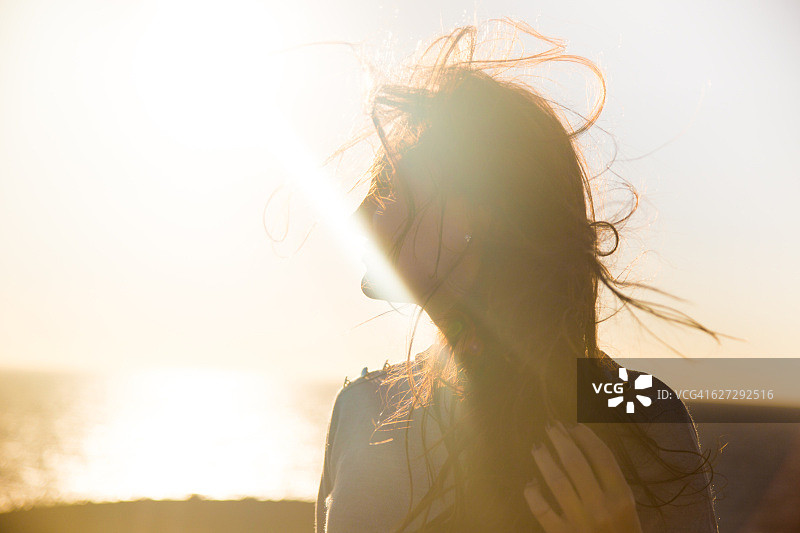 美丽的肖像，一个女孩在一个风的一天在兰萨罗特岛与美丽的强烈的阳光和风玩她的头发。图片素材