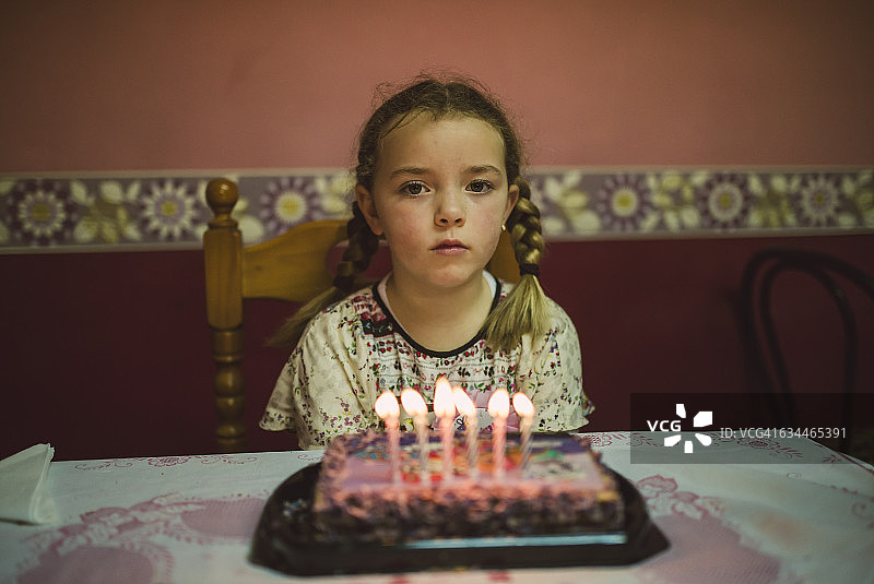 悲伤的小女孩拿着生日蛋糕的肖像图片素材