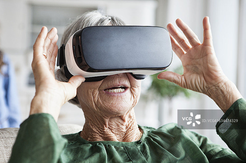 高级女性在家里使用虚拟现实眼镜图片素材