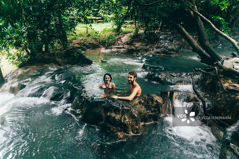 一对夫妇在温泉瀑布中沐浴图片素材