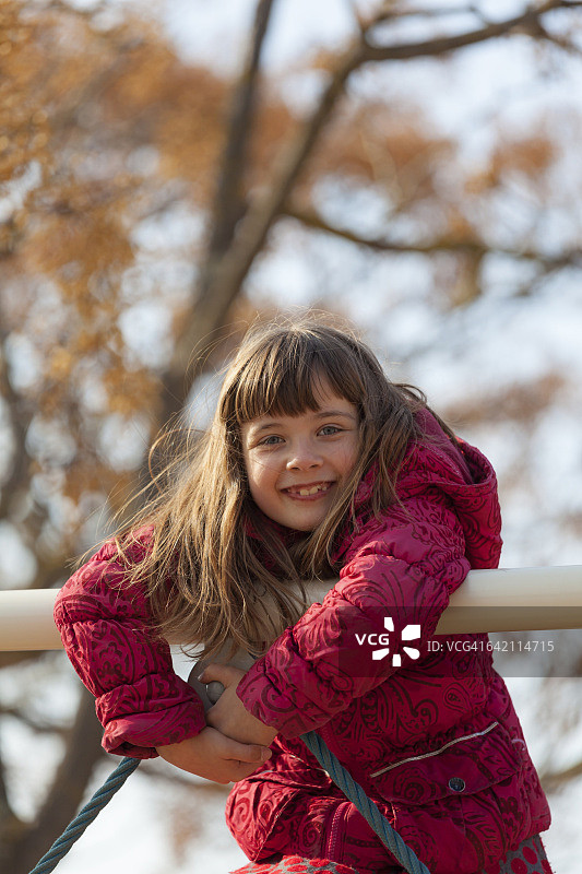 微笑的小女孩在操场上爬的肖像图片素材
