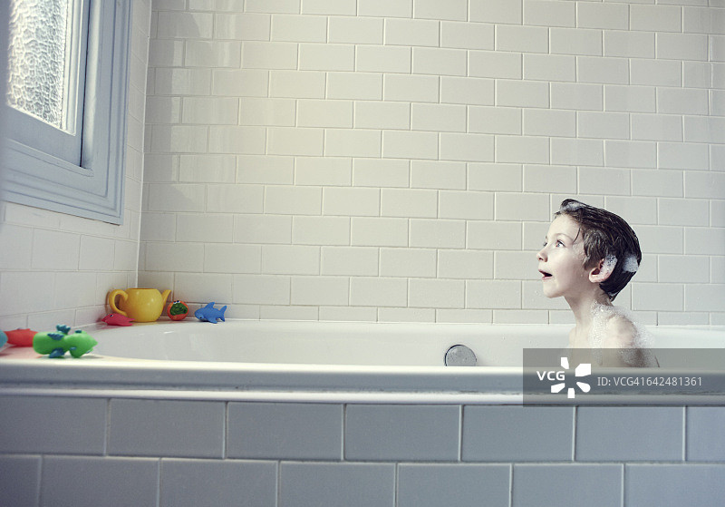 在浴缸里凝视窗外的男孩图片素材