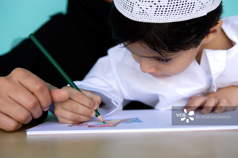 一个小男孩在书上画画。图片素材