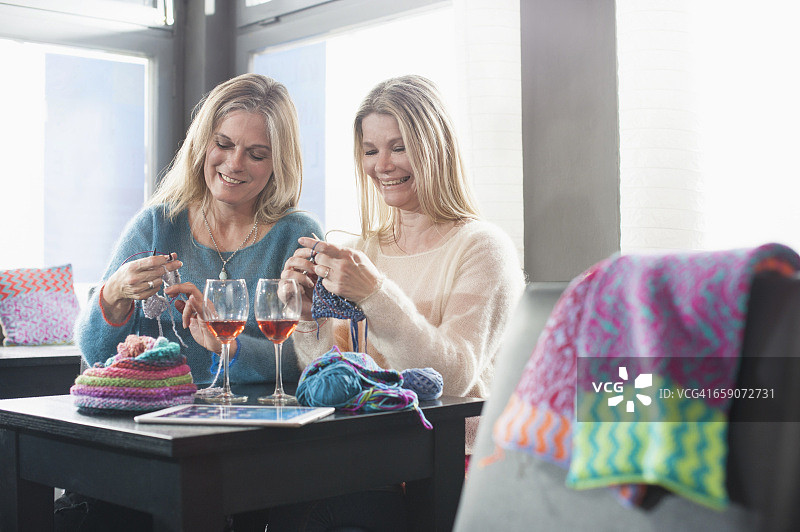 德国巴伐利亚，两名女子在咖啡店边织围巾边喝红酒，面带微笑图片素材