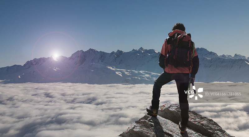 在瑞士瓦莱州的贝特梅拉普，登山者从雾中升起的山峰上望向日落图片素材