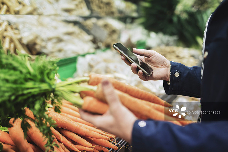 女人在超市买胡萝卜的时候用手机图片素材
