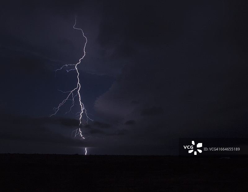 在德克萨斯州狭长地带，一个分叉的闪电从龙卷风雷暴的铁砧上划出弧线图片素材