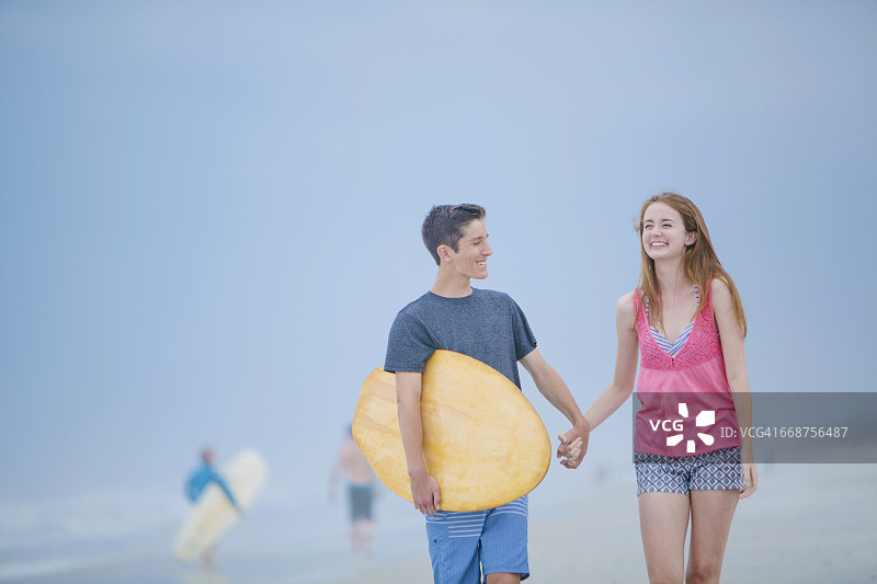 青少年情侣(16-17岁)在海滩上散步图片素材