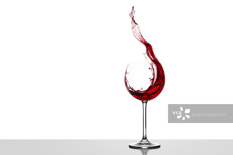 在白色背景下，红酒在玻璃杯中飞溅图片素材