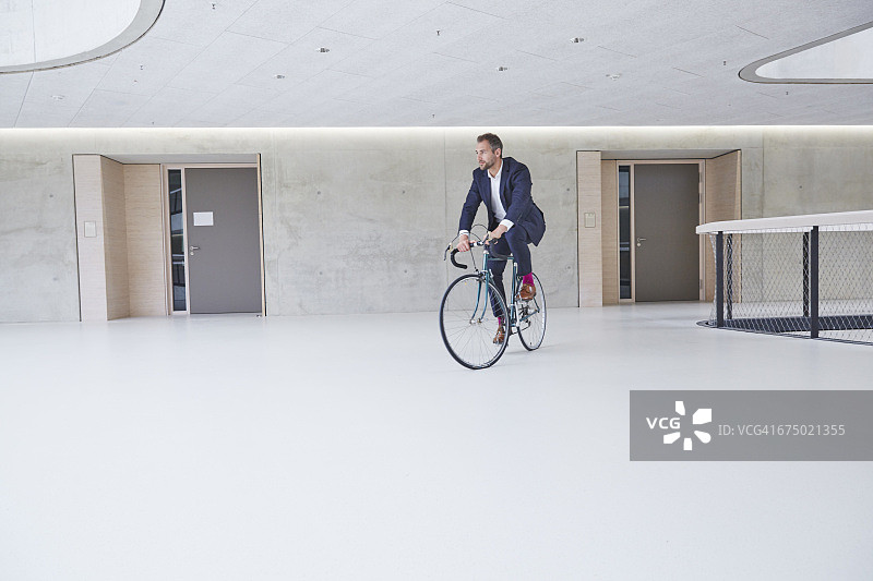 在办公楼里骑自行车的商人图片素材