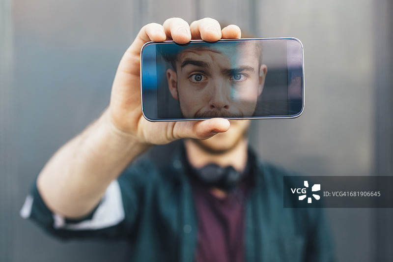 智能手机显示年轻人做鬼脸图片素材