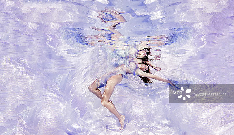 水下的观点，女人披着薄纱织物，浮向水面图片素材