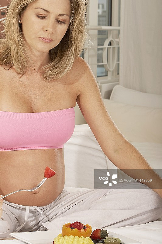 一个孕妇用叉子拿着草莓的特写图片素材