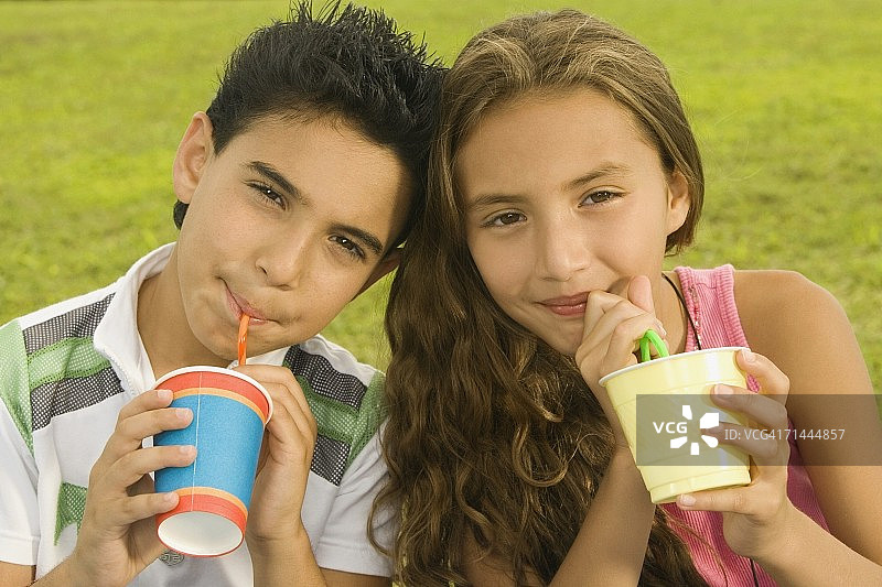 一个男孩和一个女孩用吸管喝酒的特写图片素材
