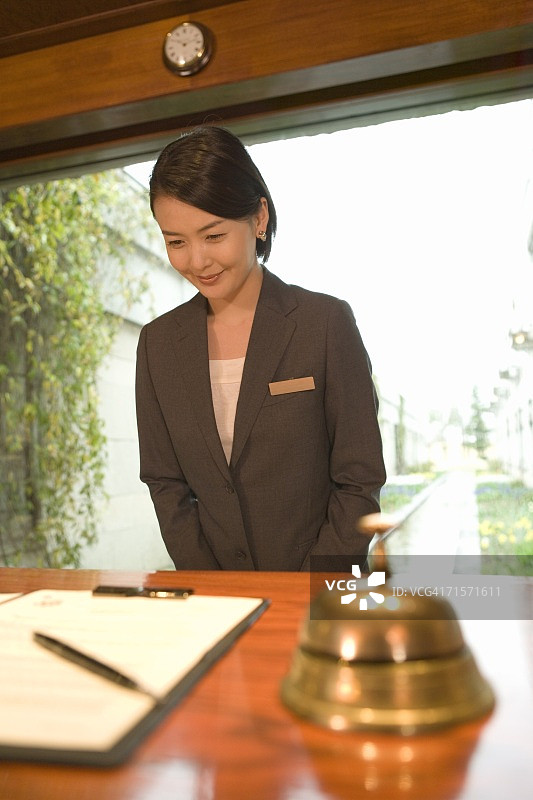 前台女接待员欢迎客人到酒店，侧视图图片素材