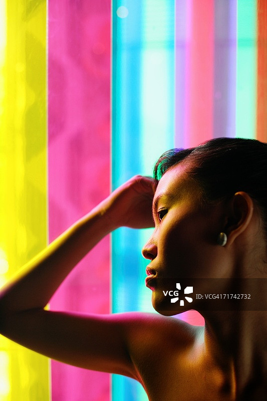 一名妇女，双手抱头，靠在彩色玻璃上图片素材