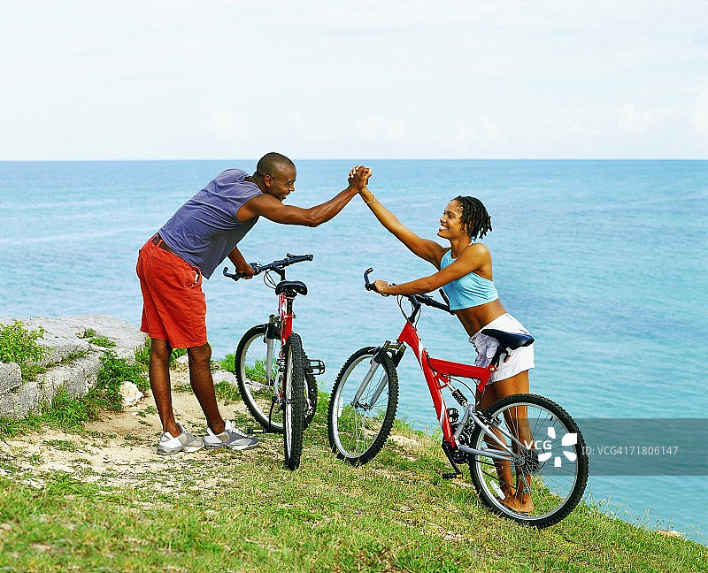 侧面的一对年轻夫妇牵着手附近的自行车，百慕大图片素材