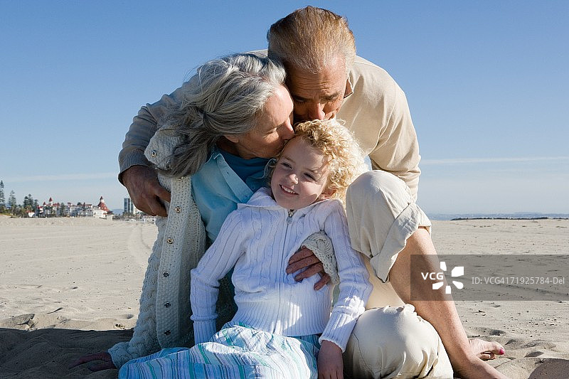 祖父母在海滩上亲吻孙女图片素材