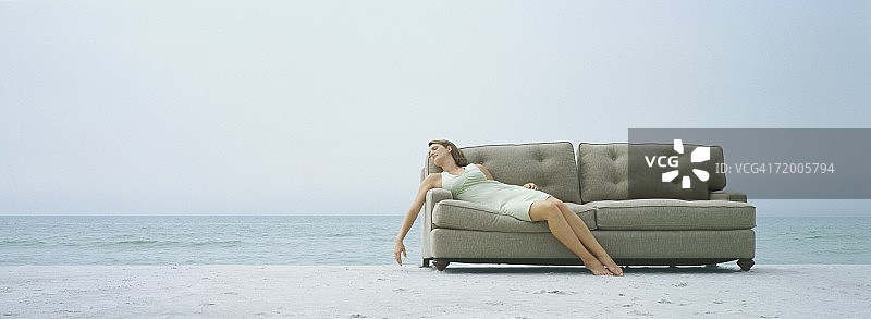 在沙滩上，躺在沙发上的女人图片素材
