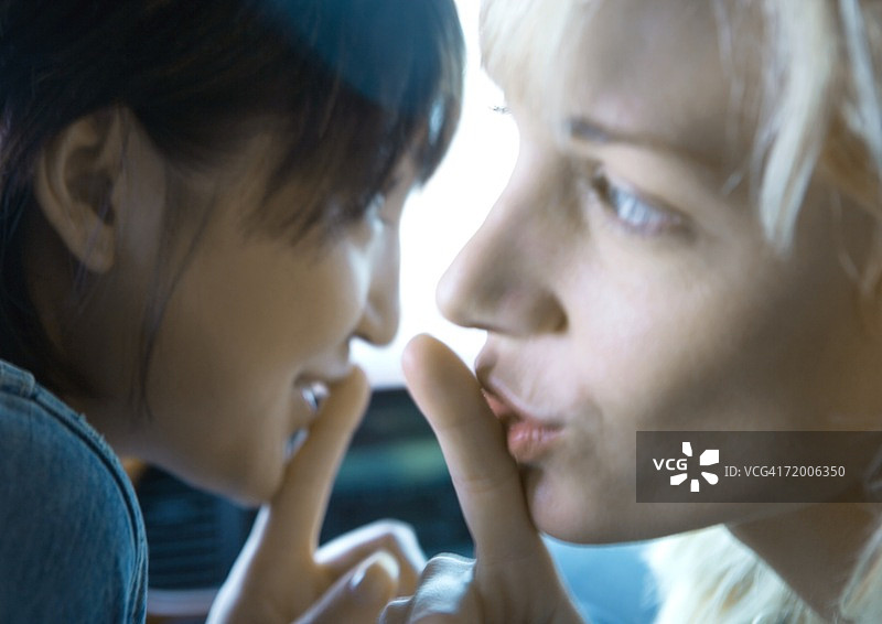两个年轻女人把手指放在嘴唇上图片素材