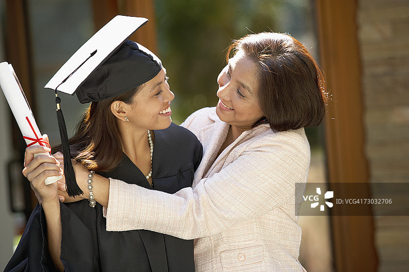 母亲拥抱穿着毕业礼服的女儿图片素材