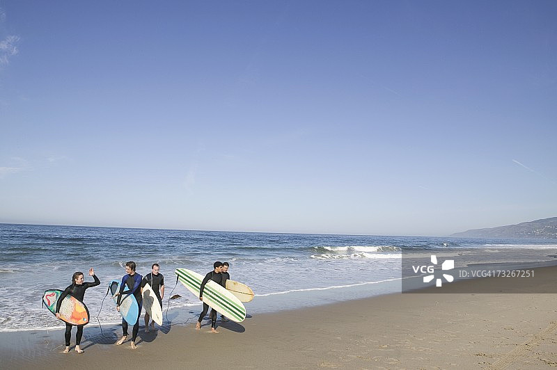 一群冲浪者带着冲浪板离开大海图片素材