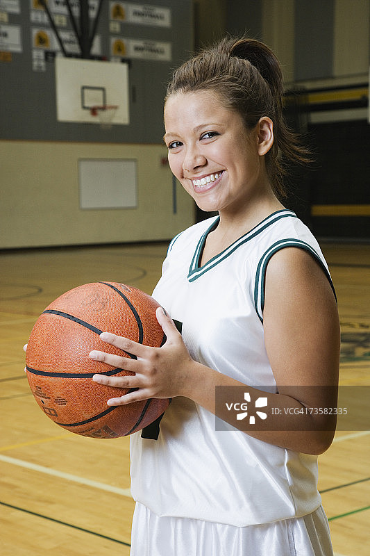 少女(14-16岁)拿着篮球，微笑着，肖像图片素材
