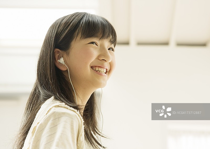 微笑的女孩用耳机听音乐图片素材