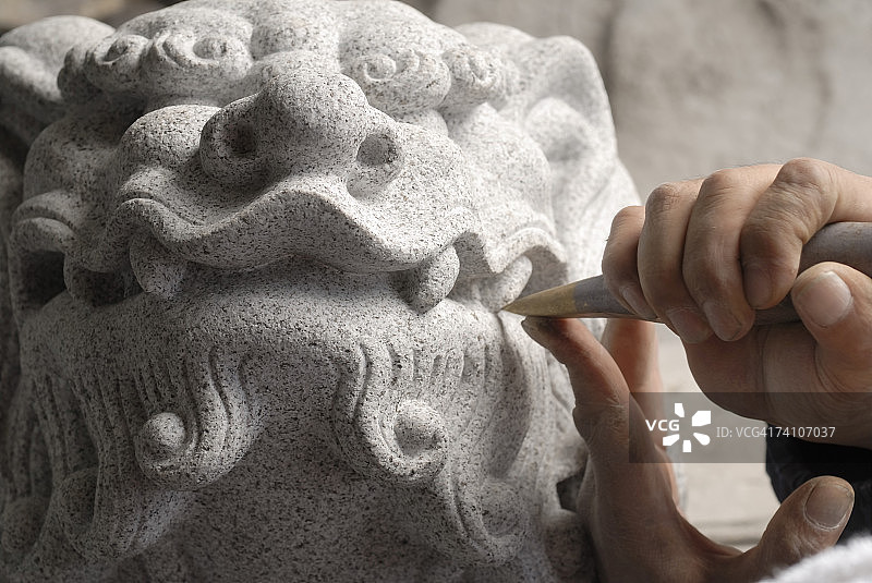 一个人用凿子雕刻雕像的手的特写图片素材