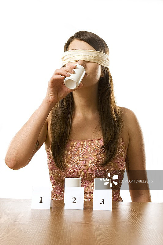 年轻女子蒙着眼睛参加了味觉测试，画像图片素材