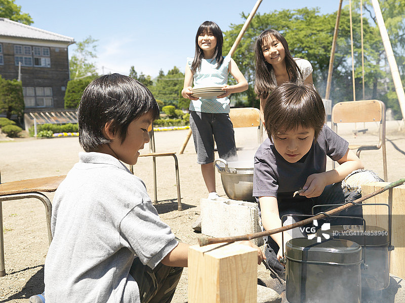 四个孩子(5-9岁)在学校操场做饭图片素材