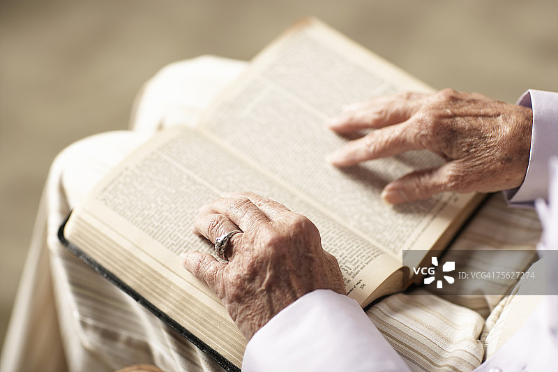 年长妇女阅读圣经，中间部分，手的特写，高角度的视图图片素材