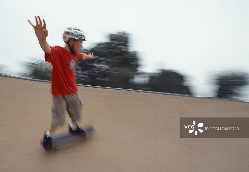 男孩(12-13岁)在斜坡上玩滑板，动作模糊图片素材