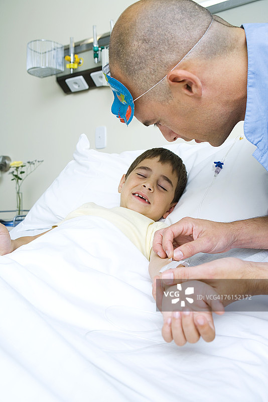 "男孩躺在病床上，护士正在调整静脉注射"图片素材