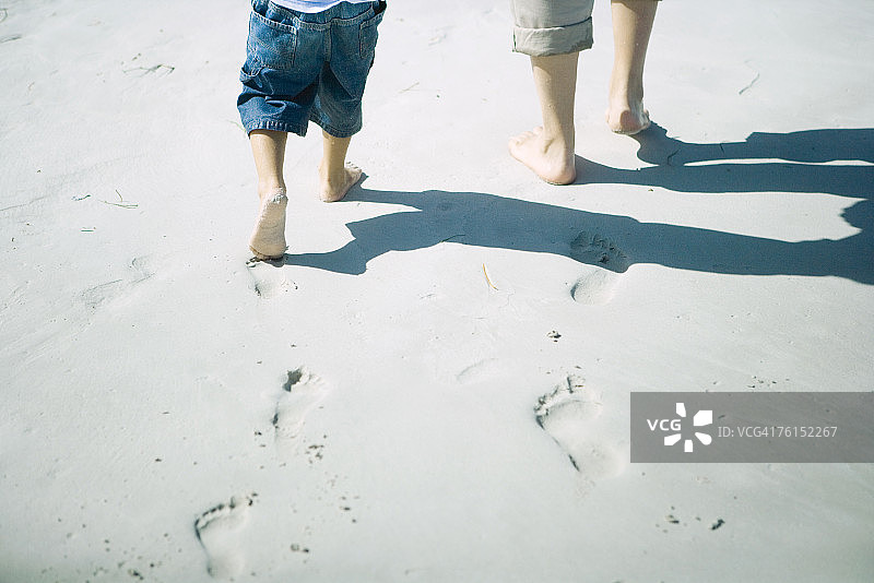 "儿童和成人在沙地上行走，地势较低"图片素材