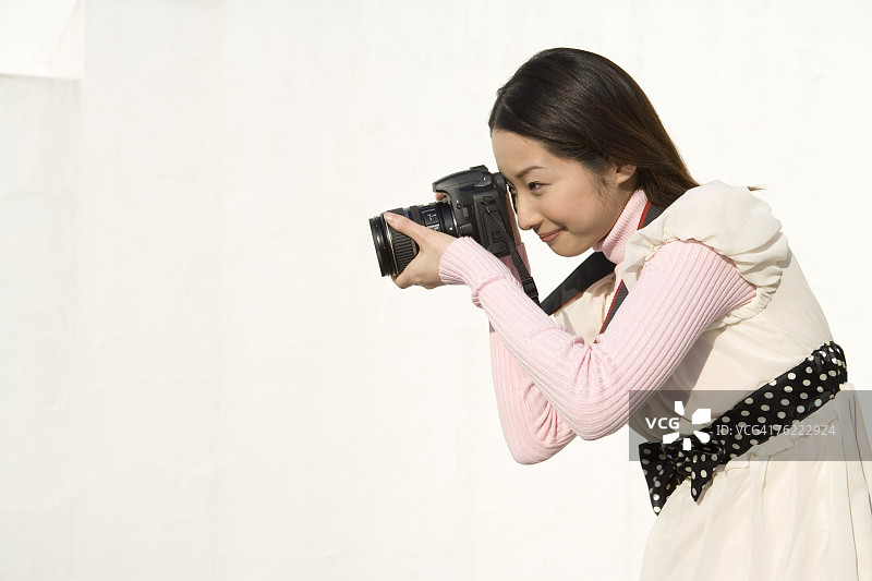一个女人在拍照，侧面，白色背景图片素材