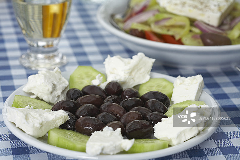 盘子上有橄榄羊乳酪和黄瓜，希腊沙拉和松香为背景。图片素材