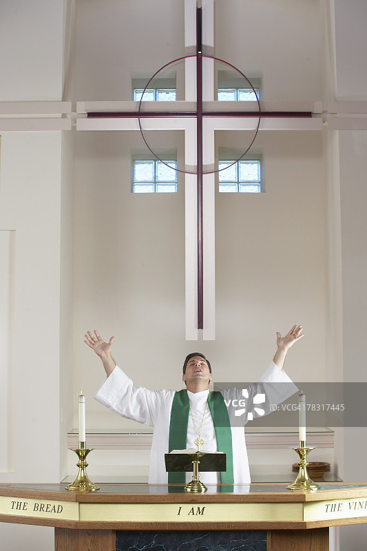 在教堂祭坛前伸出双臂的牧师图片素材