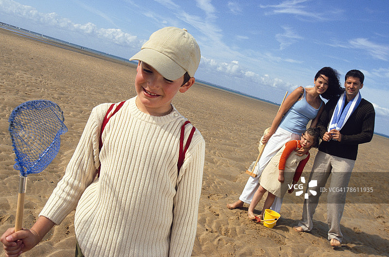 带着渔具的微笑男孩和家人在海滩图片素材