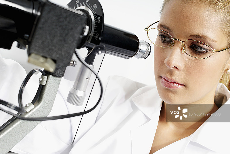 一个女性验光师通过检眼镜检查的特写图片素材