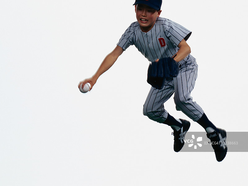 年轻的棒球运动员戴着手套在半空中接球图片素材
