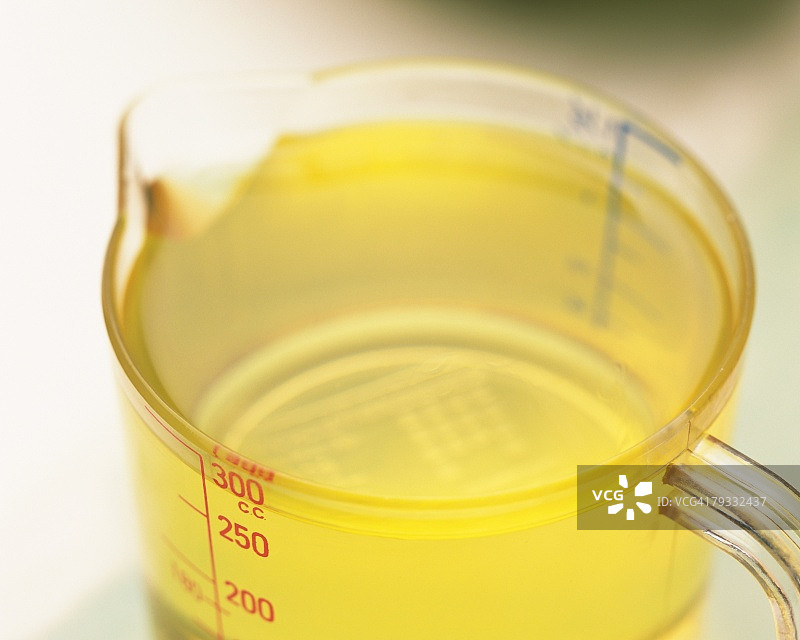 一些淡黄色的油在一个量杯，高角度视图，差焦的特写图像图片素材