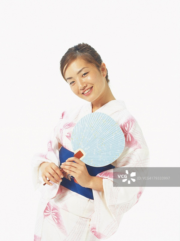 一个女人在浴田微笑着，拿着一个日本扇子，正面视图图片素材